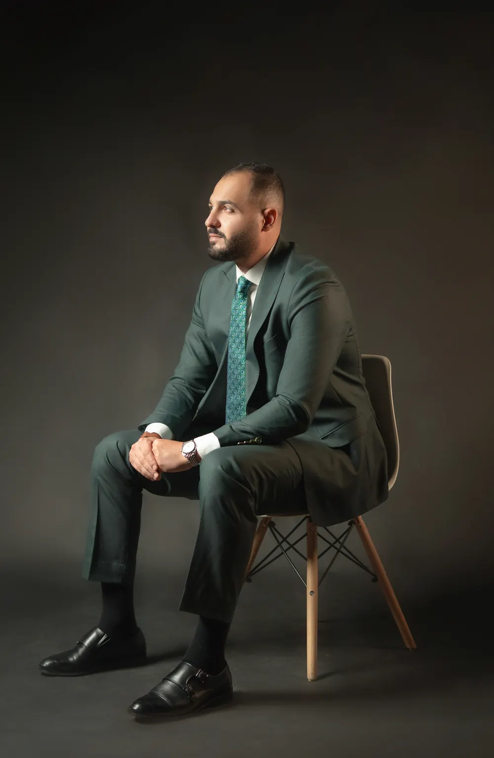 Othman Ballout, seated, looking away from the camera in a dark studio.
